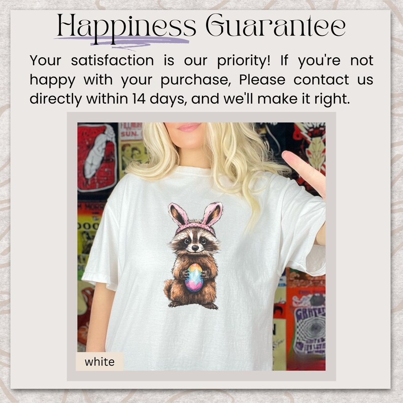 May include: White t-shirt featuring a cartoon raccoon wearing pink bunny ears and holding a colorful Easter egg. The text "Happiness Guarantee" is at the top of the image.