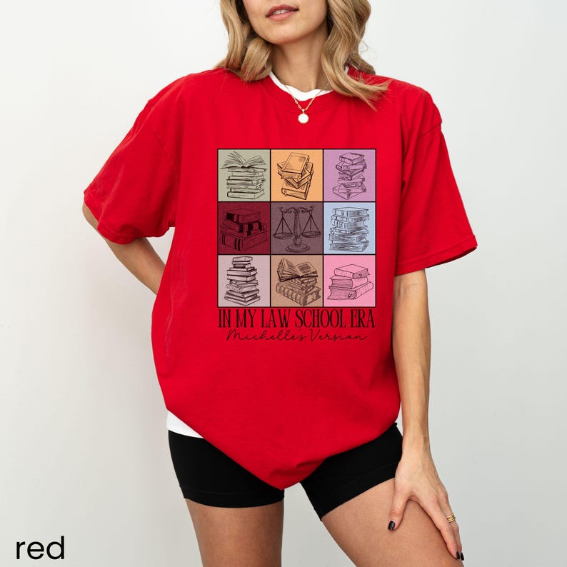 May include: Red t-shirt featuring a graphic of stacked books and the text "In My Law School Era" and "Michelle's Version".