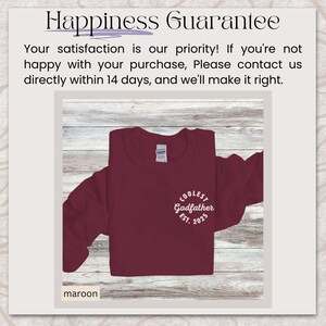 May include: A maroon long-sleeve t-shirt with the text "COOLEST Godfather EST. 2025" printed in white on the front.