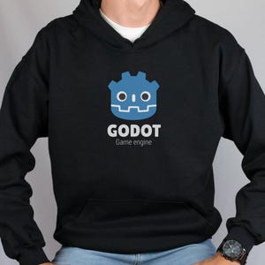 May include: Black hoodie with a blue Godot game engine logo featuring a robot face. The text "GODOT Game engine" is printed below the logo.
