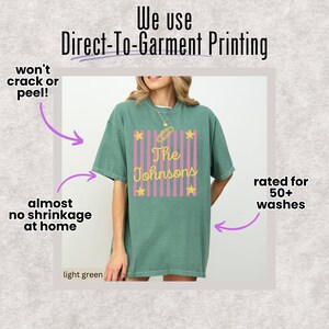 May include: A light green t-shirt featuring a graphic with vertical pink stripes, yellow stars, and the text "The Johnsons" in yellow script. The image includes text stating "We use Direct-To-Garment Printing," "won't crack or peel!," "almost no shrinkage at home," and "rated for 50+ washes."