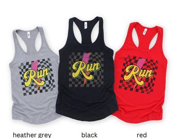 May include: Three racerback tank tops with a checkered pattern and the word "Run" in a retro font. The tank tops are in heather grey, black, and red.