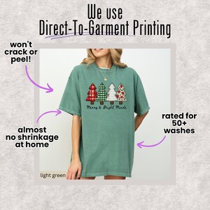 May include: Light green t-shirt featuring four Christmas trees with plaid and floral patterns. The text "Merry & Bright Minds" is below the trees. The shirt is printed using Direct-To-Garment Printing and is rated for 50+ washes.