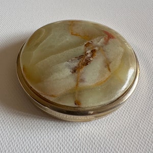 May include: A round, green and brown marble trinket box with a silver rim.