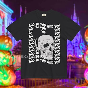 Może przedstawiać: Czarny t-shirt z kr&oacute;tkim rękawem z białą grafiką ludzkiej czaszki umieszczoną na środku klatki piersiowej. Tekst "BOO TO YOU AND YOU" jest powt&oacute;rzony w pionowym, falistym wzorze otaczającym czaszkę pogrubioną, białą czcionką bezszeryfową.
