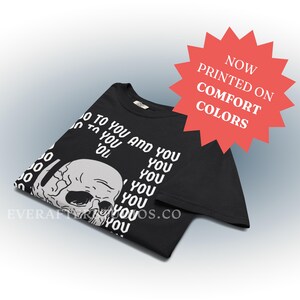 Może przedstawiać: Czarny t-shirt z białą grafiką ludzkiej czaszki i powtarzającym się tekstem 'YOU' w kolumnie, wraz z napisem 'NOW PRINTED ON COMFORT COLORS' w czerwonej gwiazdce oraz adresem strony internetowej 'EVERAFTERSTUDIOS.CO'.