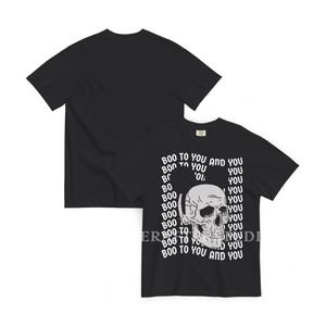 Może przedstawiać: Czarny t-shirt z kr&oacute;tkim rękawem z grafiką ludzkiej czaszki umieszczoną na środku z przodu. Tekst "BOO TO YOU AND YOU" jest powt&oacute;rzony białymi literami wok&oacute;ł czaszki. Tył koszulki jest gładki, czarny i pozbawiony jakiegokolwiek wzoru.