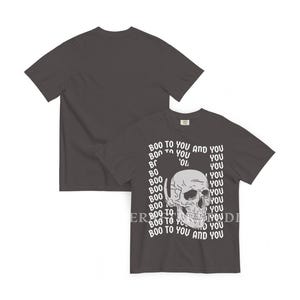 Może przedstawiać: Ciemnoszary t-shirt z kr&oacute;tkim rękawem z białą grafiką ludzkiej czaszki umieszczoną na środku z przodu. Czaszka jest otoczona powtarzającym się białym napisem "BOO TO YOU AND YOU" ułożonym w pionowy wz&oacute;r wok&oacute;ł centralnej ilustracji.