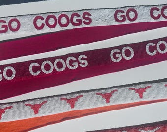 May include: Close-up of several beaded belts with team-themed designs. One belt reads "GO TEXANS" with a football graphic. Other belts feature "GO COOGS" and longhorn symbols. The belts are in various colors, including navy, red, and orange.