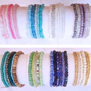 May include: A set of 10 colorful beaded bracelets. The bracelets are made of small, round beads in various colors, including pink, blue, green, white, and brown. The bracelets are stacked on top of each other, creating a colorful and eye-catching display.