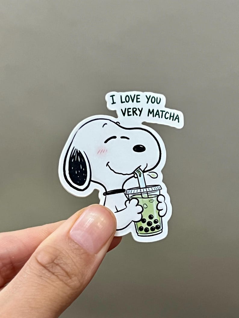 Pode incluir: Um adesivo branco de Snoopy com detalhes em preto, bebendo ch&aacute; de bolhas verde. O adesivo tem o texto "I LOVE YOU VERY MATCHA" em um bal&atilde;o de fala. Snoopy tem um rubor rosa nas bochechas.