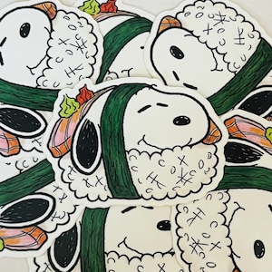 May include: A collection of stickers featuring a cartoon character designed as sushi. The stickers have a white background with a smiling face, green seaweed, and sushi toppings. The stickers are a fun, whimsical design.