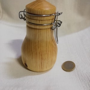 Peut inclure: Un petit pot en bois avec un couvercle à charnière et un fermoir en métal. Le pot est en bois clair avec un motif de grain naturel. Le pot est à peu près de la taille d'une pièce de monnaie.