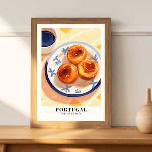 May include: A framed poster featuring a colourful illustration of three Portuguese custard tarts, or pasteis de nata, on a blue and white patterned plate. The poster has the text "PORTUGAL PASTEIS DE NATA" at the bottom.