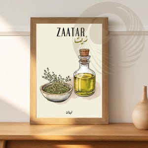 May include: A framed print with a white background featuring a hand-drawn illustration of a bowl of zaatar, a bottle of olive oil, and the word "ZAATAR" in English and Arabic. The print also includes the Arabic word for zaatar, "زَعْتَر", written in calligraphy.