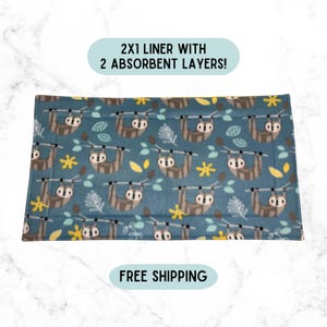 May include: A rectangular pet cage liner featuring a blue background with a repeating pattern of brown sloths hanging from branches, yellow flowers, and white leaves. The text 2X1 LINER WITH 2 ABSORBENT LAYERS! is displayed above the liner.