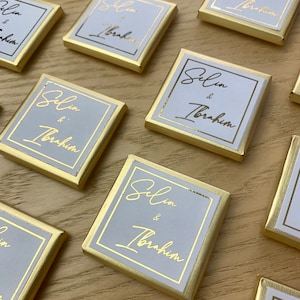 Könnte beinhalten: Goldene und weiße Geschenkboxen mit den Namen "Selim & Ibrahim" in goldener Kalligraphie.