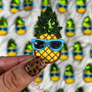 Può includere: Toppa ricamata ad ananas con occhiali da sole blu, corpo giallo e top con paillettes verdi. La toppa è tenuta davanti a uno sfondo di toppe simili. La toppa ha un contorno nero ed è un design tropicale divertente.