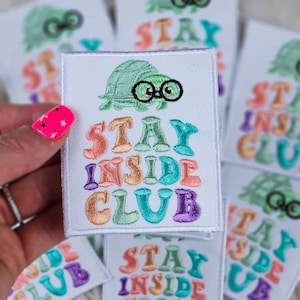 Puede incluir: Un conjunto de parches bordados para planchar que presentan una tortuga de dibujos animados con gafas y el texto "Stay Inside Club" en colores arcoíris.
