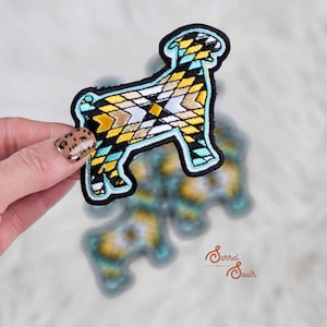May include: A turquoise, yellow, and black embroidered iron-on patch of a goat with a geometric pattern. The patch is on a white background.