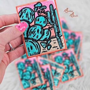 May include: A set of five embroidered iron-on patches featuring a cactus design with a pink, orange, and teal color scheme. The patches are perfect for adding a touch of southwestern style to clothing, bags, or other accessories.