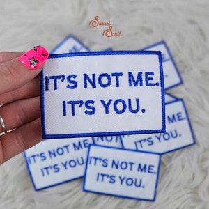 Pode incluir: Um conjunto de quatro patches termocolantes brancos com texto bordado em azul que diz "Não sou eu. É você."