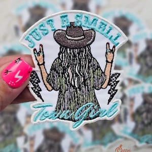 Puede incluir: Parche bordado para planchar con una niña de dibujos animados que lleva un sombrero de vaquero y una camisa de teñido anudado con el texto "Just a Small Town Girl" en letras turquesa.