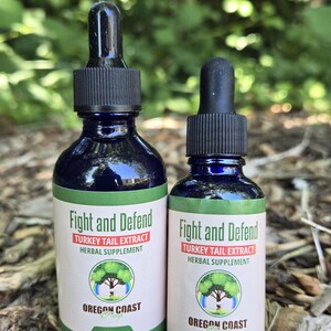 May include: Two dark blue glass bottles of herbal supplement, "Fight and Defend Turkey Tail Extract." The labels are white with red and green text, and a tree logo. One bottle is labeled "Net Wt. 2 oz" and the other "Net Wt. 1 oz."