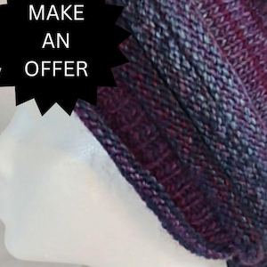 May include: A purple and blue knitted hat with a long tail. The hat is made of a soft, textured yarn.