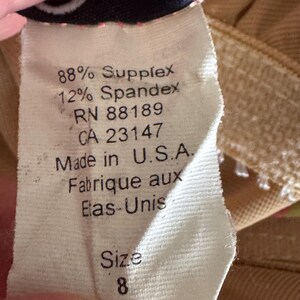 K&ouml;nnte beinhalten: Nahaufnahme eines Kleidungsetiketts mit dem Text: "88% Supplex, 12% Spandex, RN 88189, CA 23147, Made in U.S.A., Fabrique aux Elas-Unis, Gr&ouml;&szlig;e 8."