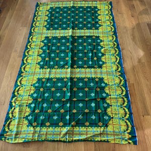 May include: A rectangular fabric textile featuring a deep green background with a repeating grid pattern of blue lines and gold fleur-de-lis symbols. The border is decorated with a wide, intricate yellow and gold paisley and floral design.