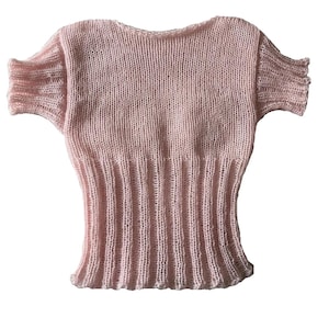 May include: A light pink short-sleeved top crafted from a sheer, fine-gauge knit fabric. The garment features a wide, ribbed-knit waistband that extends upward to the mid-torso, transitioning into a smoother, semi-sheer knit texture for the upper body.