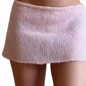 May include: A light pink mini skirt crafted from a soft, semi-sheer knitted yarn. The garment features a simple, straight-cut silhouette with a plain stockinette stitch pattern, showcasing a consistent texture throughout the entire piece.