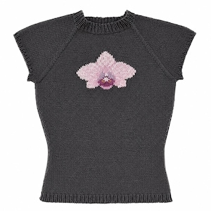 Op de afbeelding: Een donker antracietgrijs gebreid shirt met korte mouwen, een geribbelde ronde hals en een centraal intarsia-ontwerp van een lichtroze orchidee met een donkerpaars en magentakleurig hart, uitgevoerd in een gladde tricotsteek.