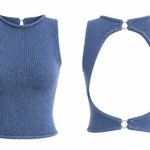 May include: A sleeveless blue knit top featuring a high neckline and a large open back design. The garment is secured at the neck and waist with circular metal rings, showcasing a ribbed texture throughout the front and back panels.