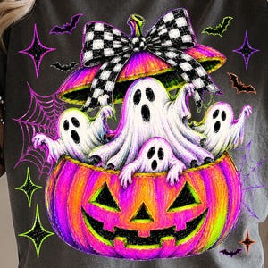 May include: A charcoal gray t-shirt featuring a graphic of a bright pink and yellow jack-o'-lantern filled with three white ghosts. The pumpkin is topped with a black and white checkered bow, surrounded by purple spiderwebs, bats, and stars.