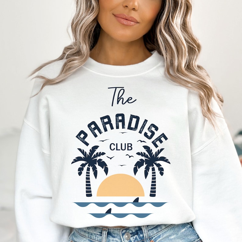 May include: White sweatshirt with a blue graphic print of palm trees, a sunset, and the text "The Paradise Club".