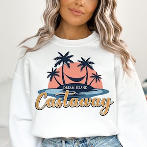 May include: White sweatshirt with a graphic of palm trees, a hammock, and a sunset. The text "Dream Island Castaway" is printed below the graphic.