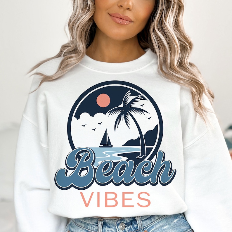 May include: White sweatshirt with a blue and pink graphic of a palm tree, sailboat, and the words "Beach Vibes".
