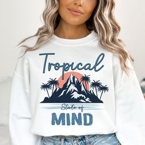May include: White sweatshirt with a blue and pink graphic design that says "Tropical State of Mind". The graphic features a mountain, palm trees, and a sunset.