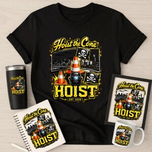 Op de afbeelding: Zwart T-shirt met een grafisch ontwerp met oranje verkeerskegels, een lasmasker en een doodshoofd met gekruiste botten. De tekst "Hoist the Cone" en "HOIST EST. 2026" zijn ook afgebeeld. Extra items zijn een tumbler, notitieboek, ingelijste print en mok.