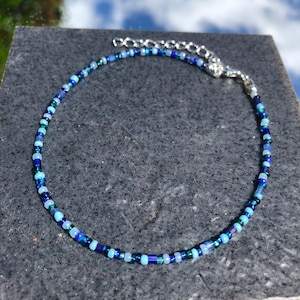 May include: A delicate blue and green beaded choker necklace with a silver clasp.