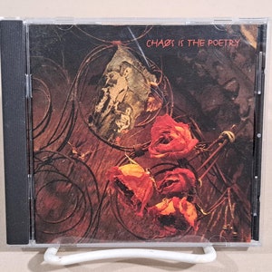 May include: A CD case with a red, white, and brown image of dried roses and a piece of paper with the text "Chaos is the Poetry".