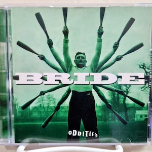 May include: A CD case with a green background and a man with multiple arms holding baseball bats. The text "BRIDE" is in white letters and the text "ODDiTiFS" is in white letters on a black background.