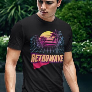 Peut inclure: Un t-shirt noir avec un motif rétro de palmiers, un coucher de soleil et un motif de grille. Le texte "RETROWAVE" est imprimé dans une police audacieuse et colorée.