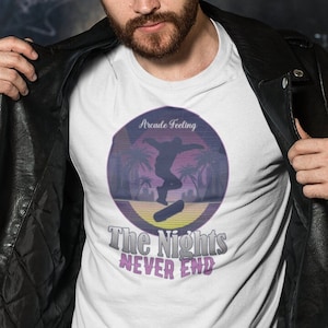 May include: A white t-shirt with a retro-style graphic of a person skateboarding in front of palm trees. The graphic has the text "Arcade Feeling" and "The Nights Never End".
