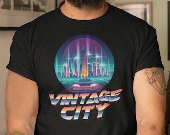 Könnte beinhalten: Ein schwarzes T-Shirt mit einem Grafikdruck einer futuristischen Skyline in einem Kreis mit dem Text "Vintage City" darunter. Die Stadt ist im Retro-Stil der 80er Jahre mit Neonfarben dargestellt.