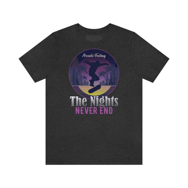 May include: Dark heather grey t-shirt with a retro-style graphic of a person skateboarding in front of palm trees. The graphic has a purple and pink color scheme and the text "Arcade Feeling" and "The Nights Never End".