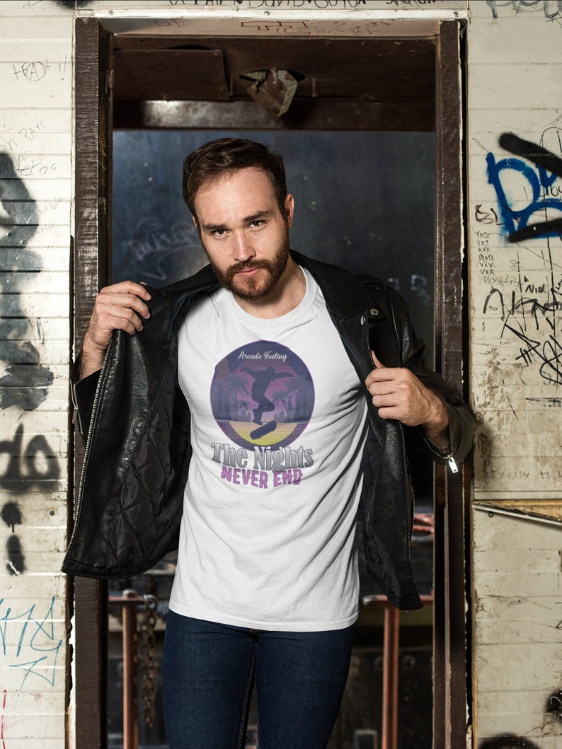 May include: A white t-shirt with a retro-style graphic of a person skateboarding in front of palm trees. The graphic has the text "Arcade Feeling" and "The Nights Never End".