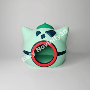 May include: A light green, 3D-printed Bulbasaur planter with a red-rimmed opening. The planter has dark blue accents and a green top. The text "Etsy Novinity3D" is visible on the side.